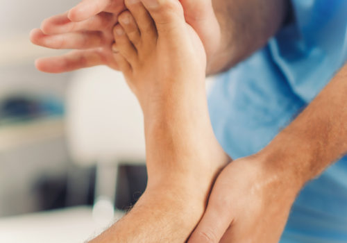 Physiotherapist doing healing treatment on patient foot. Therapist wearing blue uniform. Osteopathy, Chiropractic foot adjustment