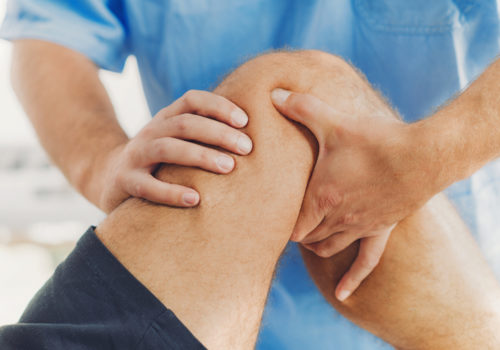 Physiotherapist doing healing treatment on patient leg. Therapist wearing blue uniform. Osteopathy, Chiropractic leg adjustment