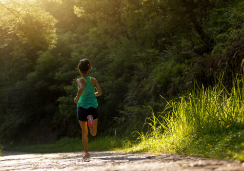 Young fitness woman athlete running on forest trail